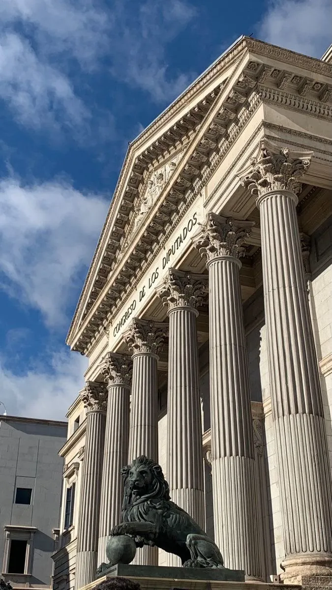 A bronze lion guarding a neoclassical portico with Corinthian columns
